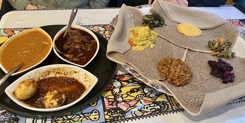 Doro wot with hard-boiled egg, shiro and vegetarian sides on injera